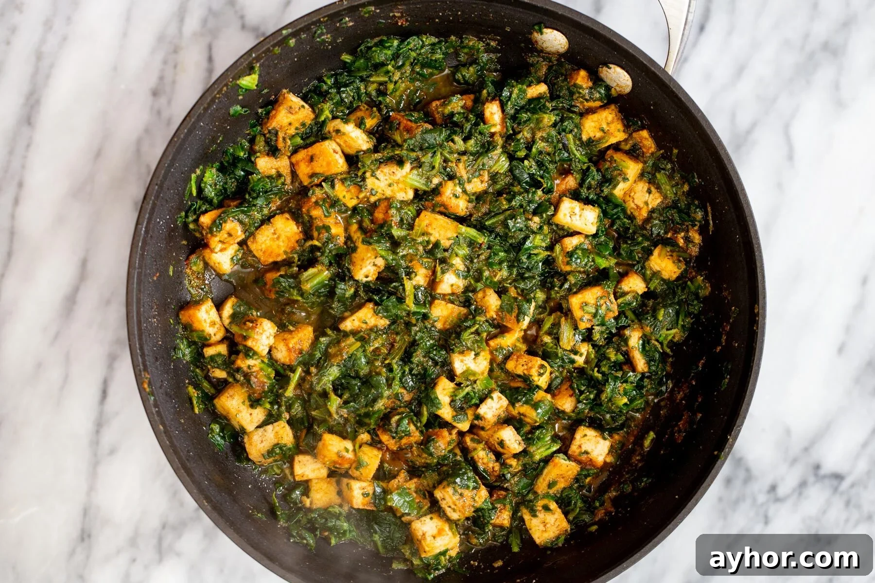 overhead shot of tofu cubes and spinach in a skillet 