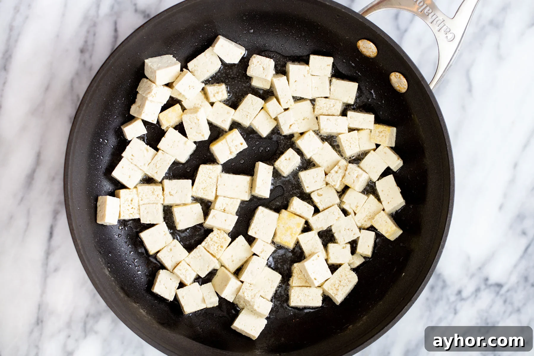 tofu cubes frying in a sauteeing pan 