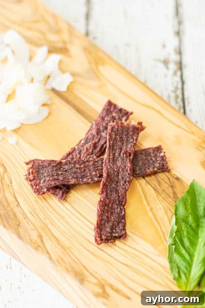 Coconut-Infused Ground Beef Jerky 2 coconut ground jerky on cutting board with coconut shavings and basil