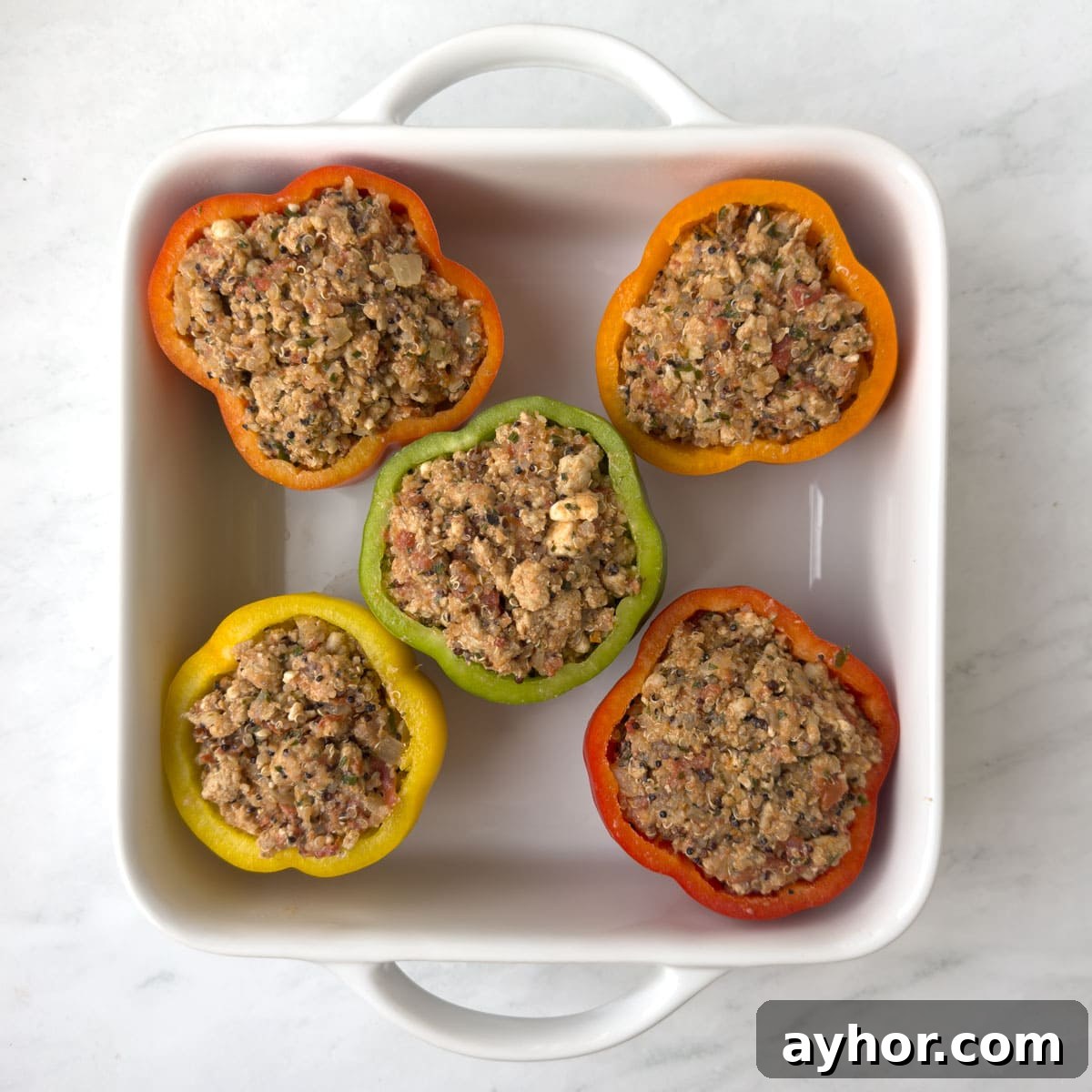 Ground Turkey Stuffed Peppers with Savory Tomato Rice 8 Raw stuffed peppers ready for the oven and baking in a white casserole.