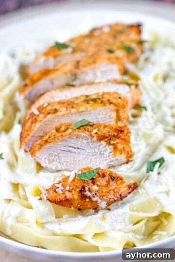 Air fryer chicken alfredo in a white pasta bowl, garnished with fresh herbs.