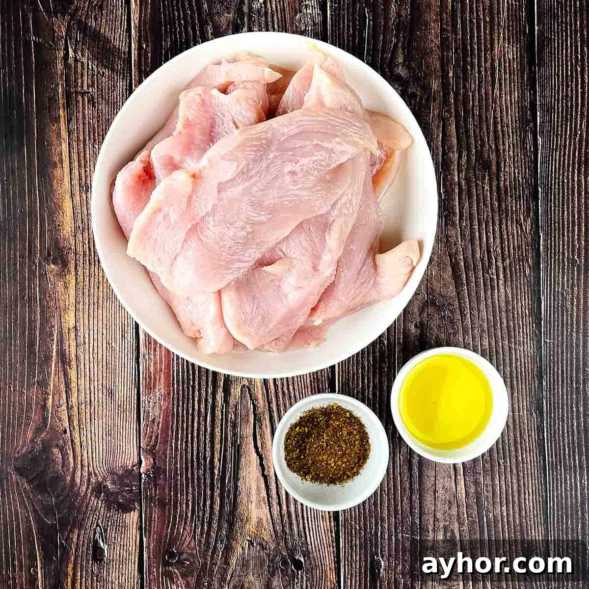 Ingredients for thin air fryer chicken breasts on a wooden table.