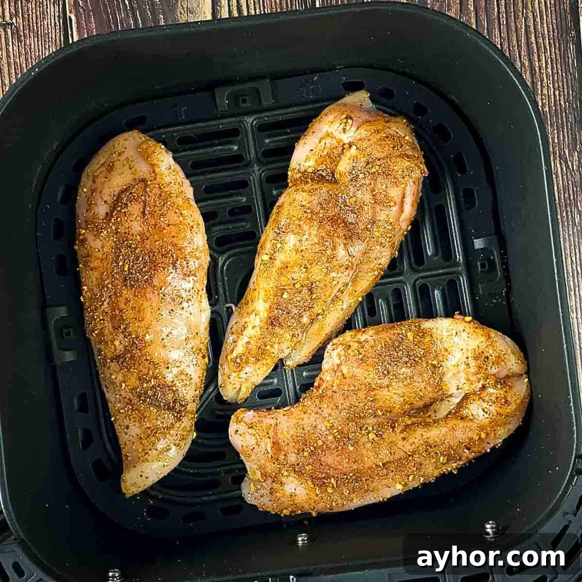 Seasoned chicken breasts in the air fryer basket.