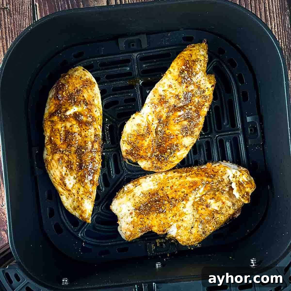 Thin chicken breasts cooked in the air fryer basket.