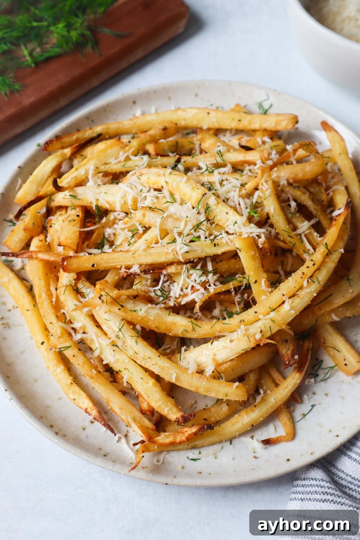 Crispy Air Fryer Roasted Parsnips Recipe 2 white plate with air fried parsnips topped with fresh herbs and cheese