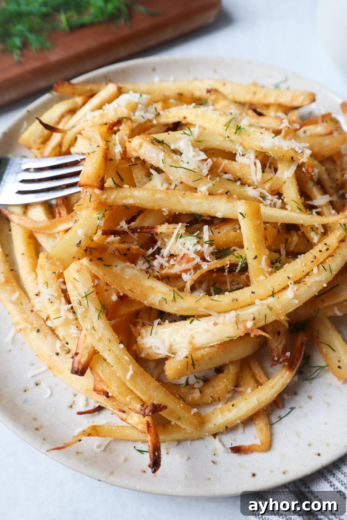Crispy Air Fryer Roasted Parsnips Recipe 4 white plate with air fried parsnips topped with fresh herbs and cheese
