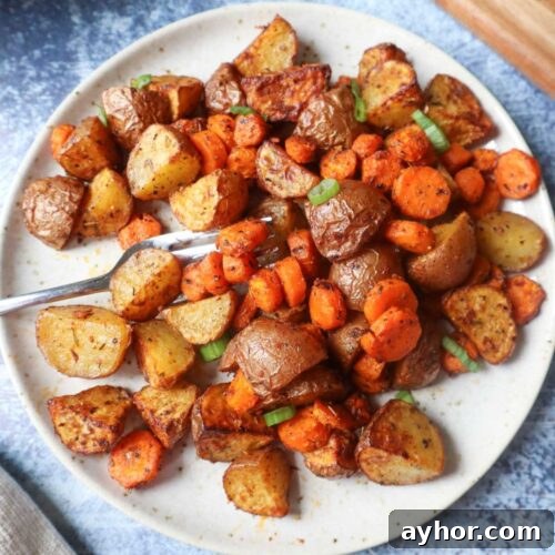 white plate with air fried carrots and potatoes topped with green onion