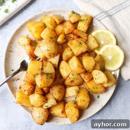 air fryer lemon greek potatoes on a white plate with two slices of lemon