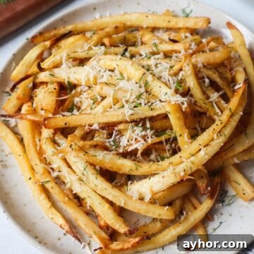 Crispy Air Fryer Roasted Parsnips Recipe 9 white plate with air fried parsnips topped with fresh herbs and cheese