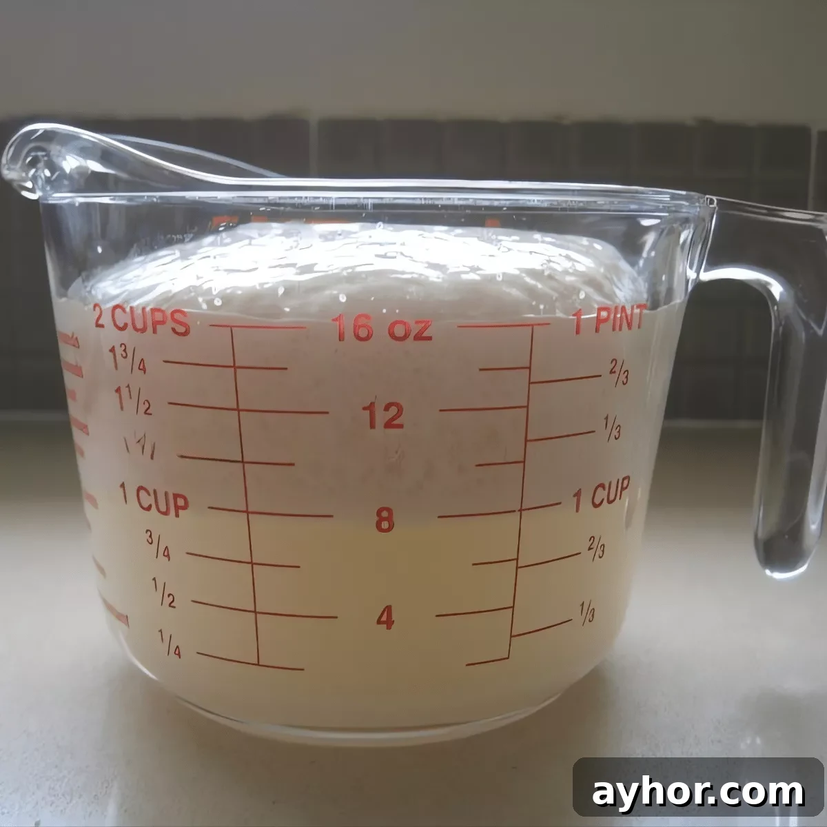 How to Make Homemade Pizza Dough from Scratch 4 Frothy yeast mixture in a measuring cup for homemade pizza dough.