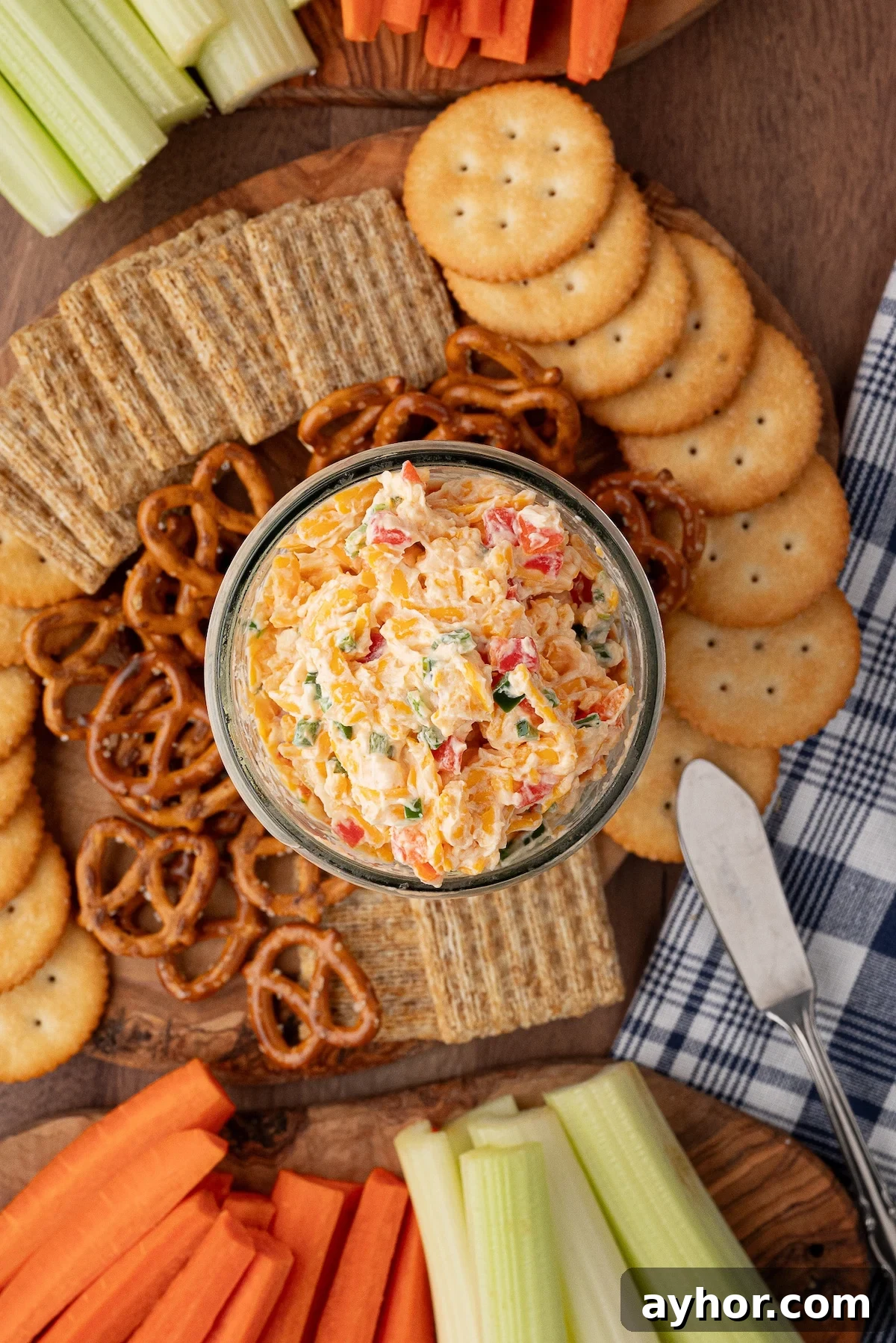 pimento cheese spread on a serving board with crackers, pretzels and crudite