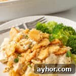 Poppy seed chicken casserole on a white plate with steamed broccoli.