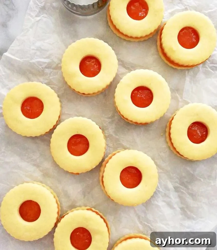 apricot jam filled sandwich cookies laid out on parchment paper close up overhead image