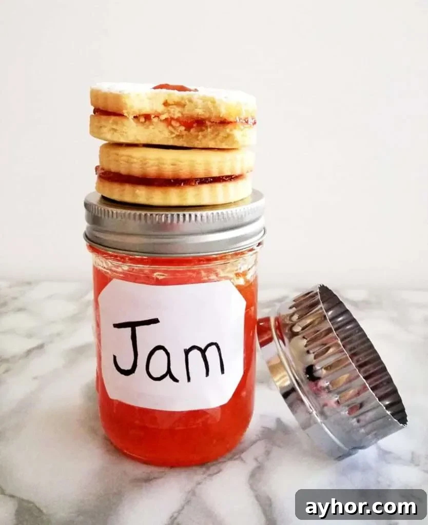 apricot jam filled sandwich cookies stacked on top of jar of jam