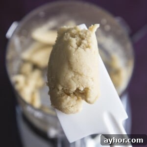 Homemade Almond Paste Recipe with Video Tutorial 7 A spatula holding a piece of almond paste just made in a food processor.