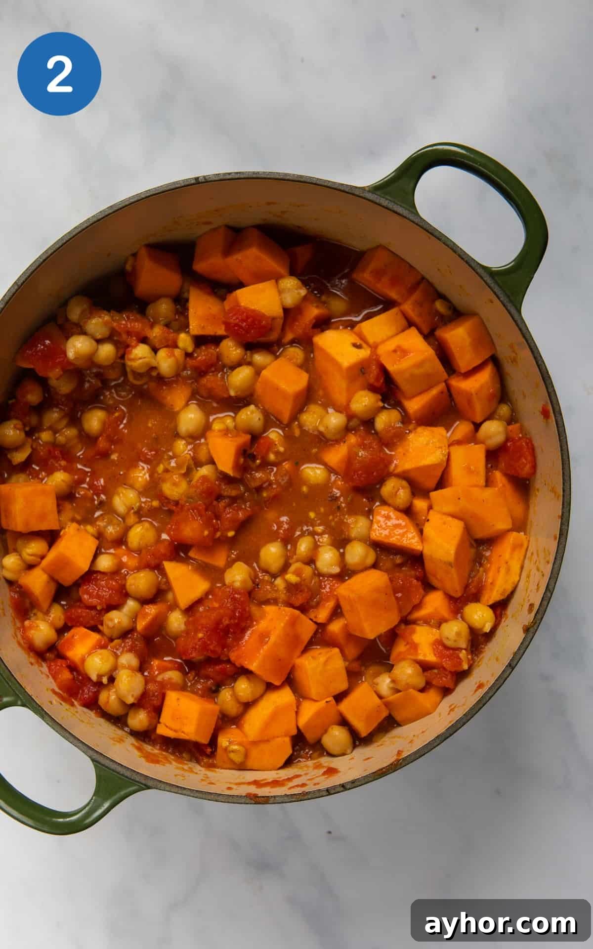 Sweet potato, chickpeas and peanut butter in a pot mixed with tinned tomatoes.