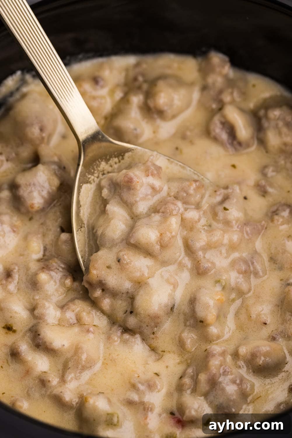 Close up image of Slow Cooker Sausage Cheese Dip being stirred