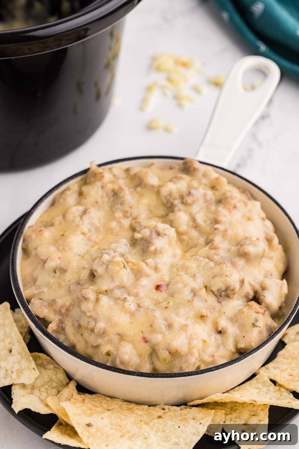 Close up image of Slow Cooker Sausage Cheese Dip served and ready to eat in a bowl with tortilla chips arranged around it