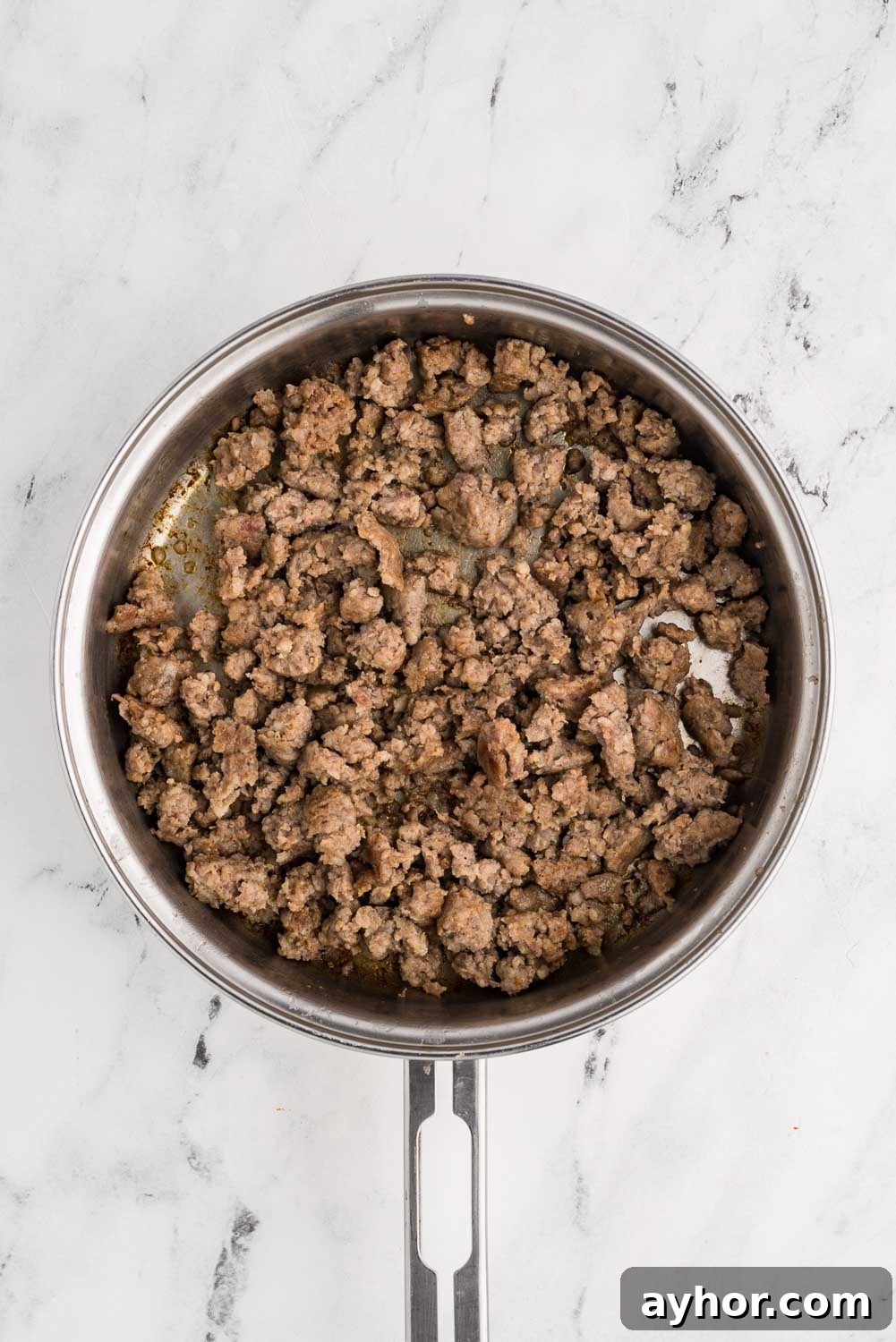 Browned sausage, broken into pieces, placed in a stainless steel skillet