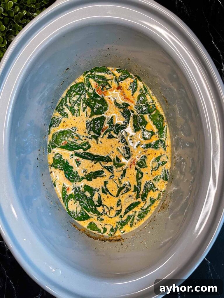 Slow Cooker Tuscan Chicken sauce in a crock pot.