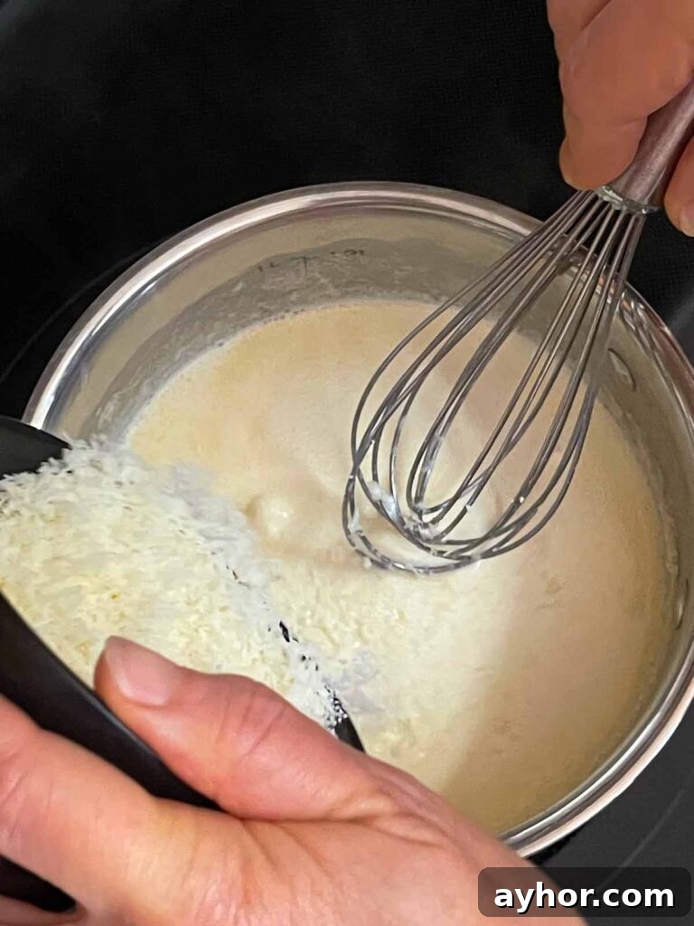 Adding parmesan cheese to the sauce for slow cooker Tuscan chicken.