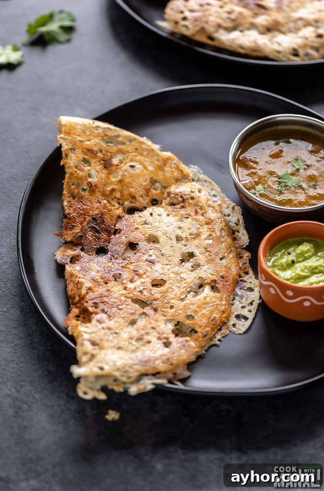 Crispy Rava Dosa: Authentic South Indian Semolina Crepes 4 rava dosa placed in a black round plate with a bowl of sambar and a bowl of chutney