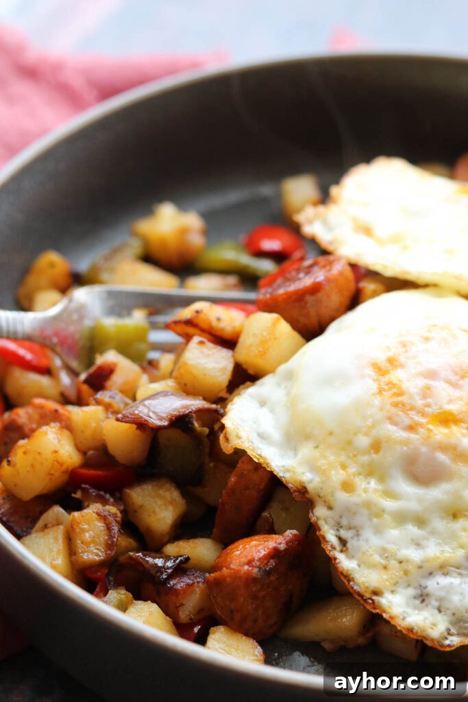 Cajun Potato Hash with Sausage and Peppers 4 cajun spiced potato hash with sausage with two eggs over medium in plate