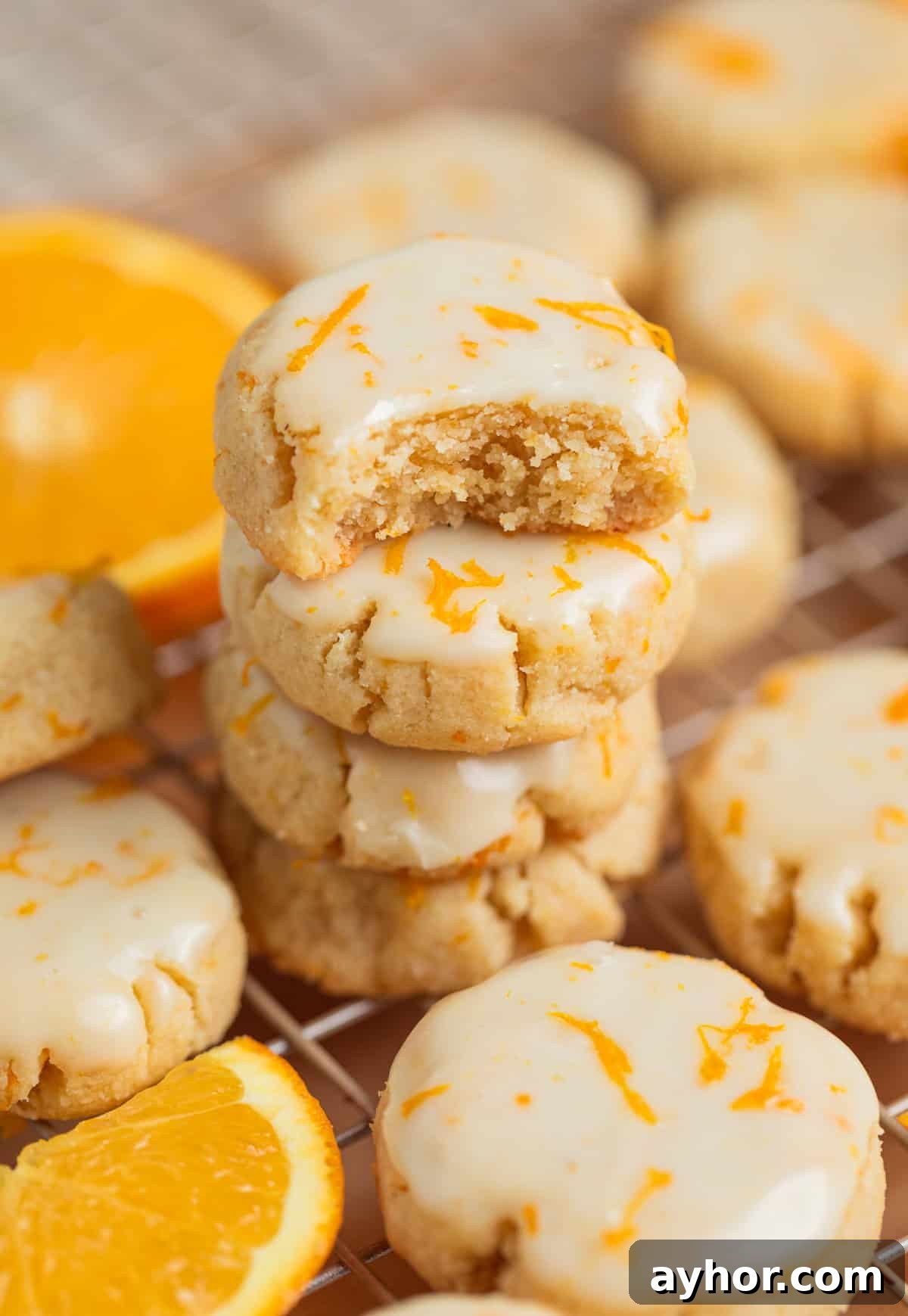 Stack of iced orange almond flour cookies with bite taken out of top cookie.