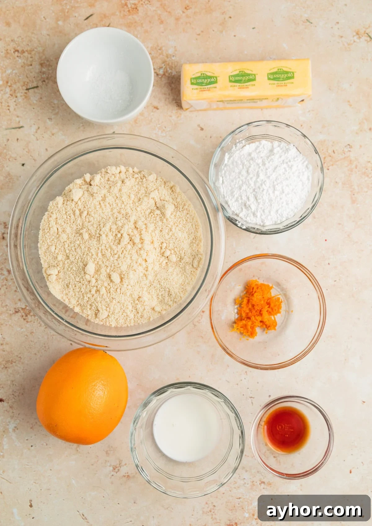 Orange, orange zest, almond flour and other ingredients on surface.
