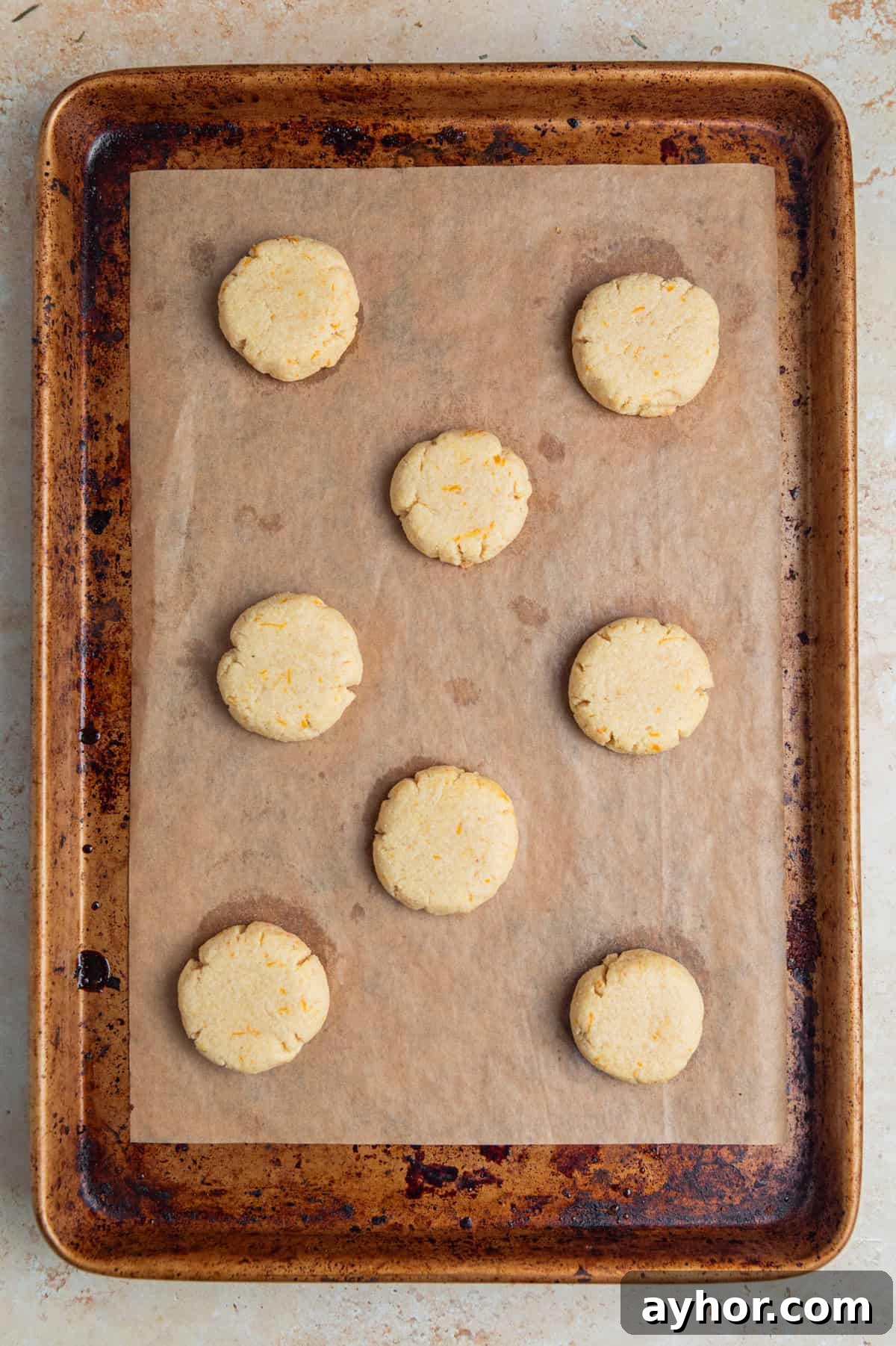 Baked orange cookies on parchment lined cookie pan.