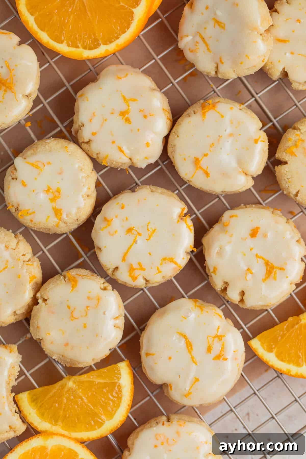 Overhead view of iced orange cookies on cooling rack.