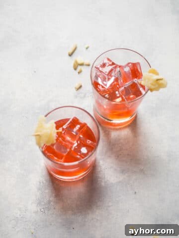 Two glasses with pink cocktails and ginger garnishes.