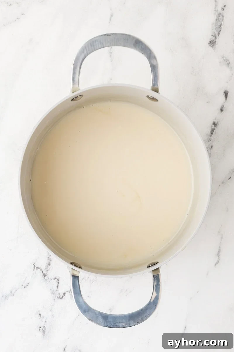 Mango Sticky Rice with Coconut Cream: Authentic Thai Dessert Recipe 9 Coconut cream mixture heating in a saucepan to make sweet sauce.