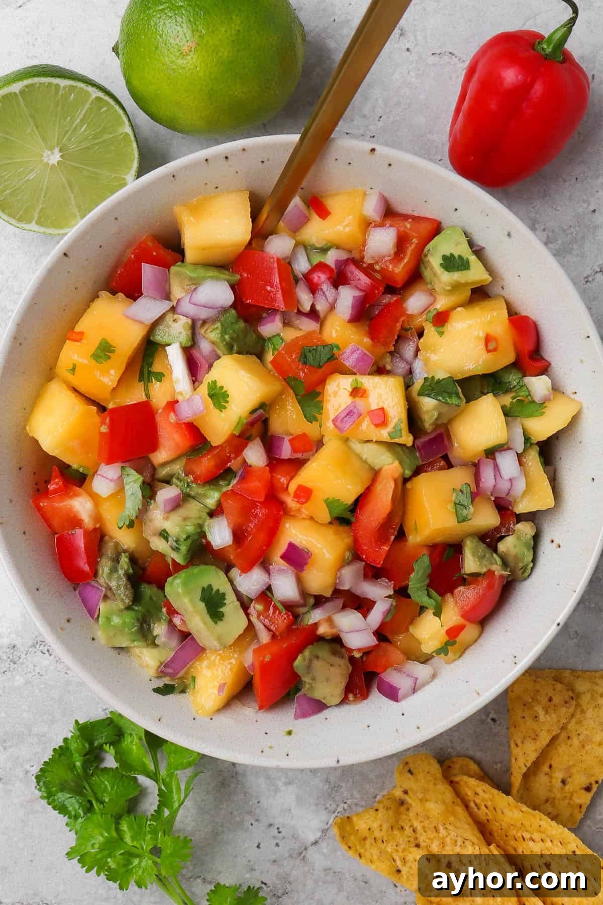 Mango salsa in a bowl with a spoon.