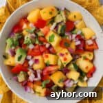 Mango habanero salsa in a bowl with corn chips around the sides.