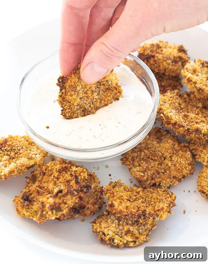 Crispy Air-Fryer Pickles: Tangy Homemade Fried Pickle Chips 7 Hand holding a fried pickle and dipping it into a small bowl of ranch.
