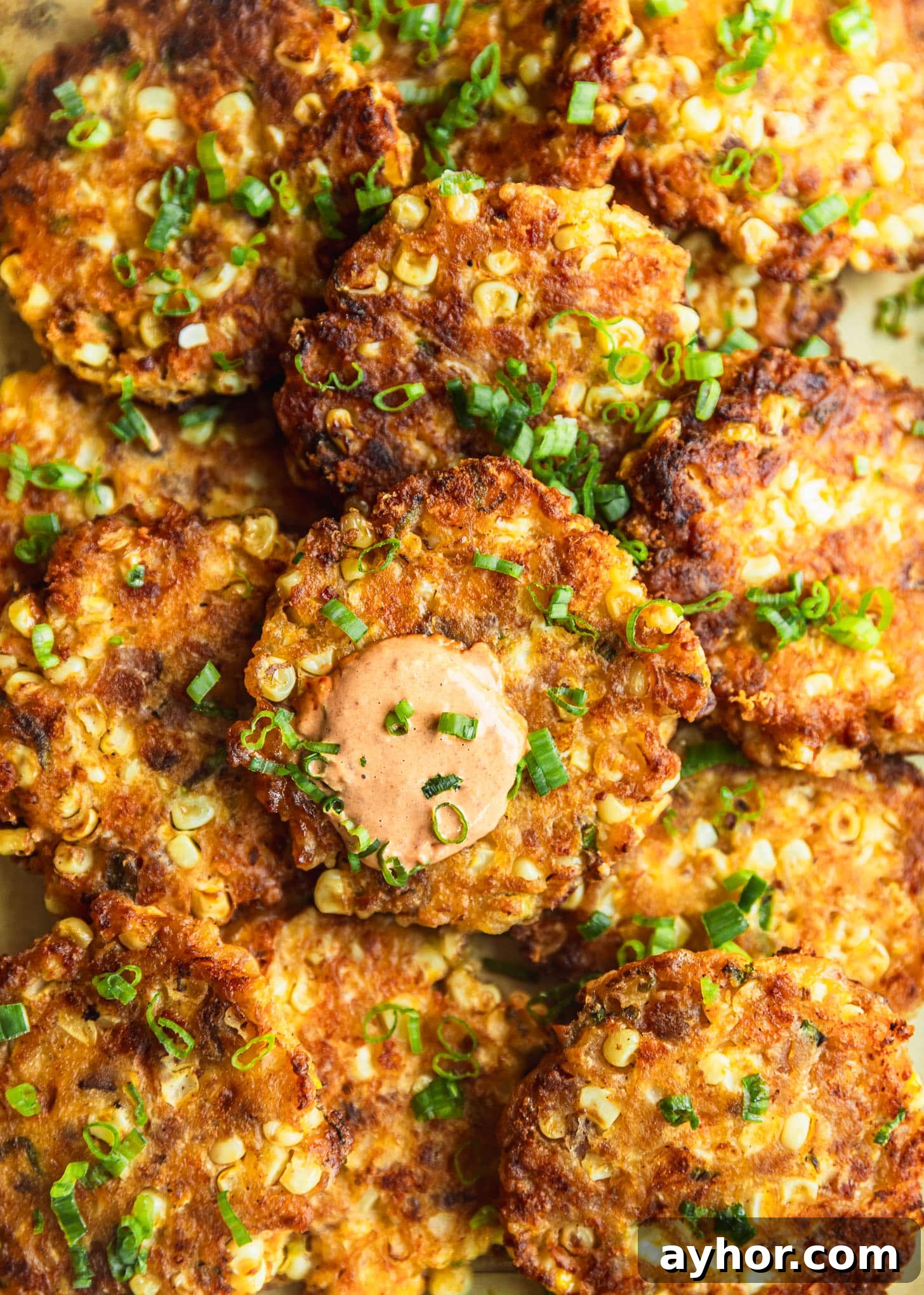 A pile of bacon and corn fritters topped with green onions.