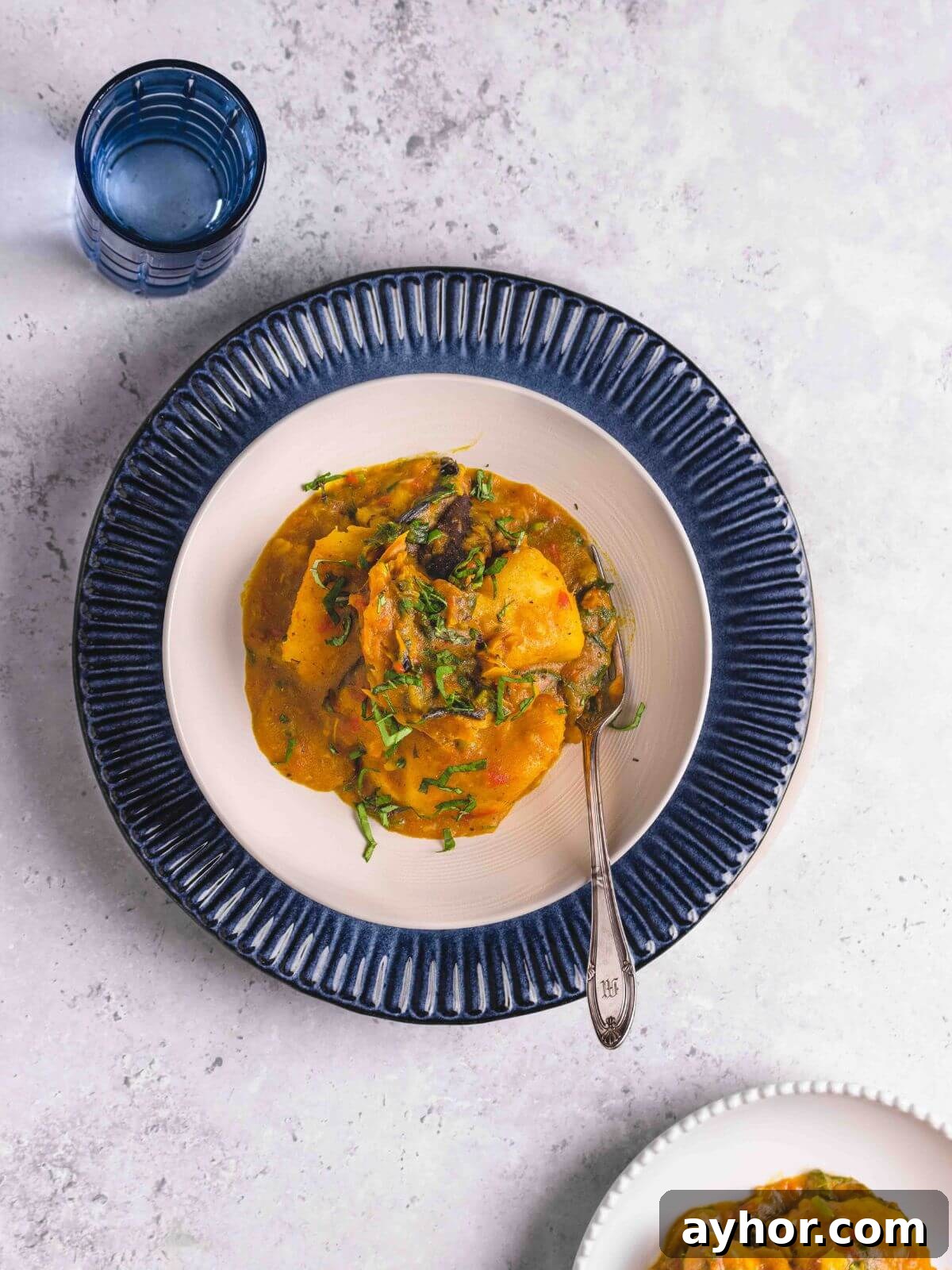 Asaro Nigerian Yam Porridge Recipe: Authentic Spicy Yam Mash 6 A serving of porridge yam in a white bowl with a glass of water.