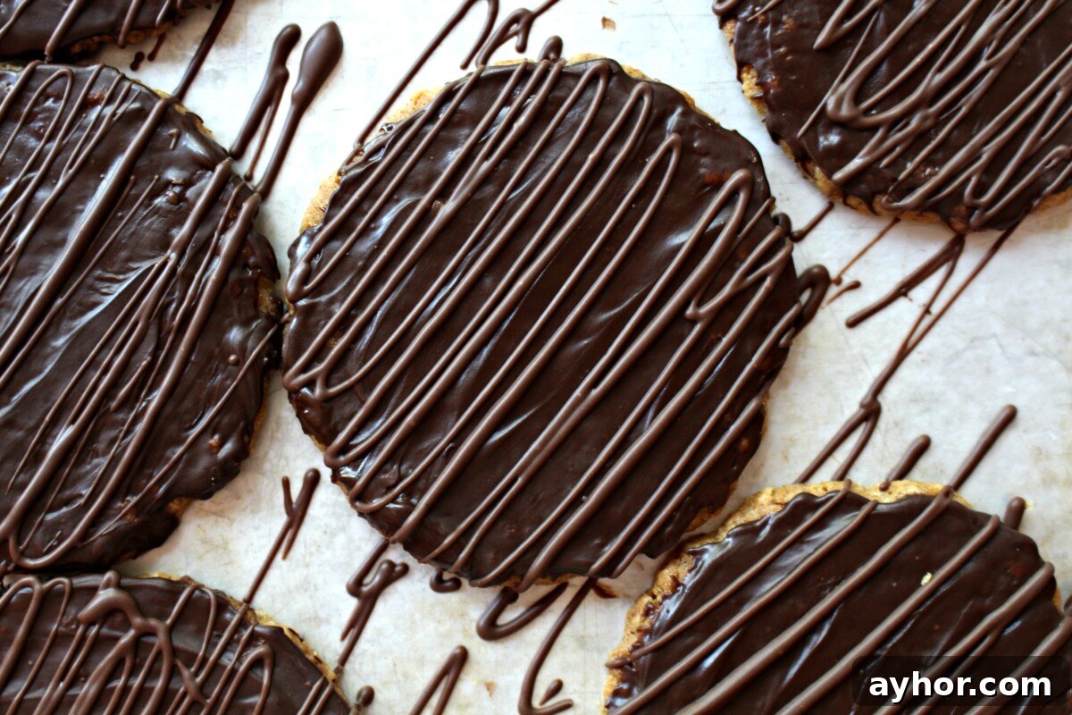 Chocolate-Covered Hobnob Oat Cookies Recipe 5 Cookies covered in chocolate then additional chocolate is zigzaged over the top.