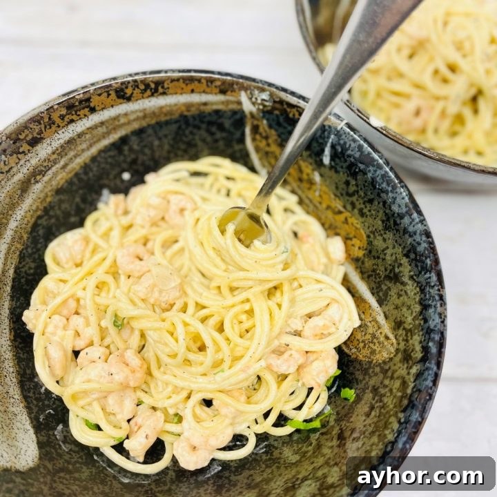 prawn spaghetti with creamy garlicky sauce served in a black bowl with a fork
