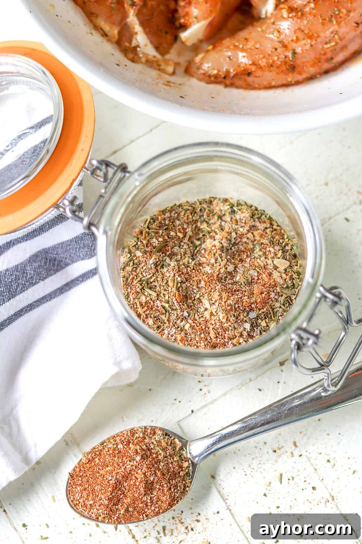 A lidded clear jar full of Montreal chicken seasoning mix.