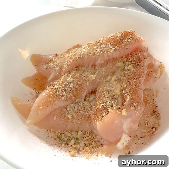 Sprinkling Montreal chicken seasoning over chicken breast tenders.