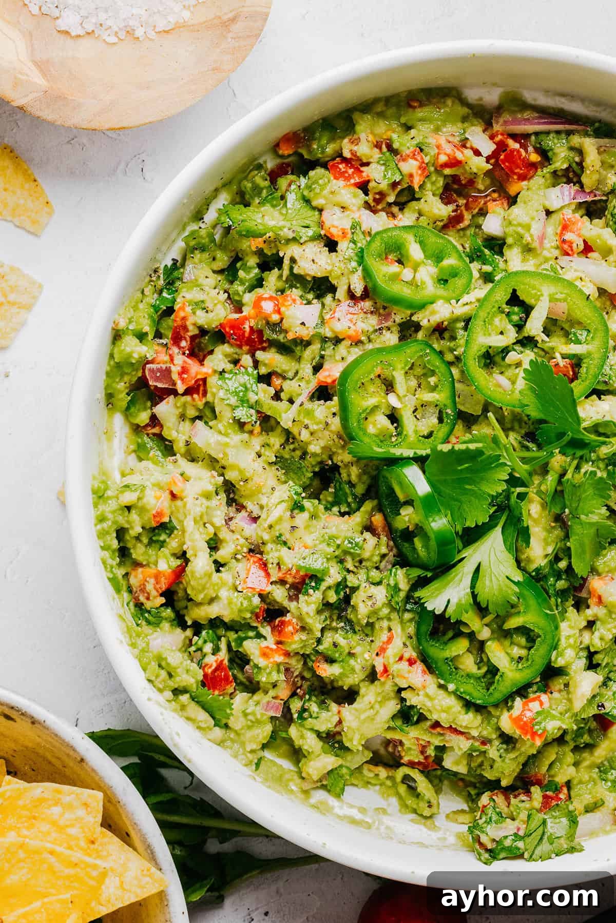 The BEST Chunky Guacamole recipe made with ripe avocados, crisp veggies, zesty lime juice and a kick of heat that you can easily throw together in just minutes! Perfect for summer barbecues, game day parties, taco nights or simply craving a fresh snack.
