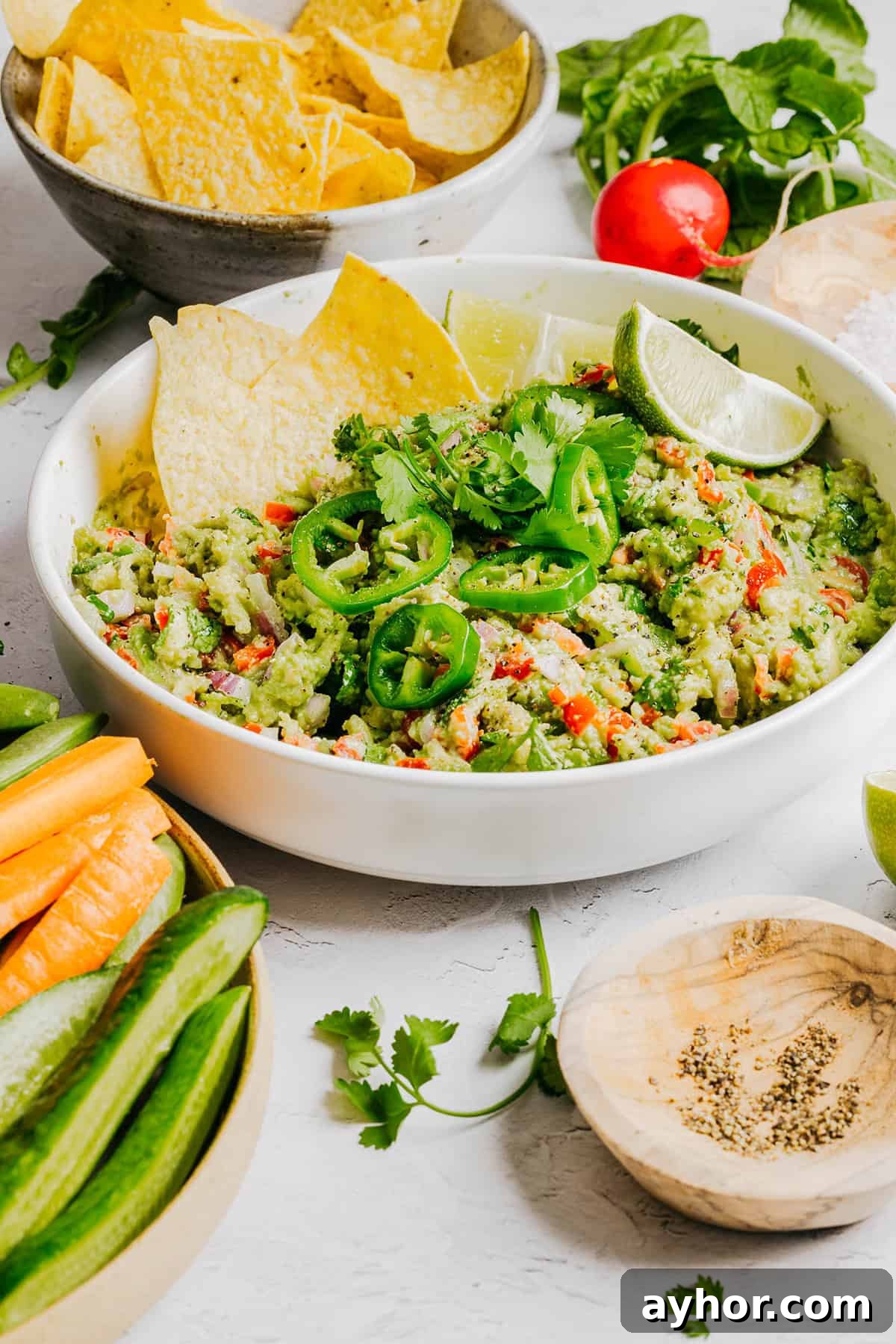 The BEST Chunky Guacamole recipe made with ripe avocados, crisp veggies, zesty lime juice and a kick of heat that you can easily throw together in just minutes! Perfect for summer barbecues, game day parties, taco nights or simply craving a fresh snack.