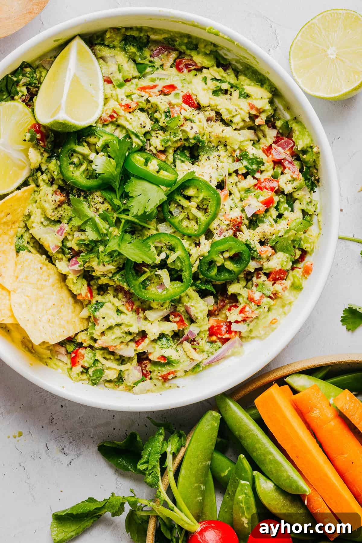 The BEST Chunky Guacamole recipe made with ripe avocados, crisp veggies, zesty lime juice and a kick of heat that you can easily throw together in just minutes! Perfect for summer barbecues, game day parties, taco nights or simply craving a fresh snack.