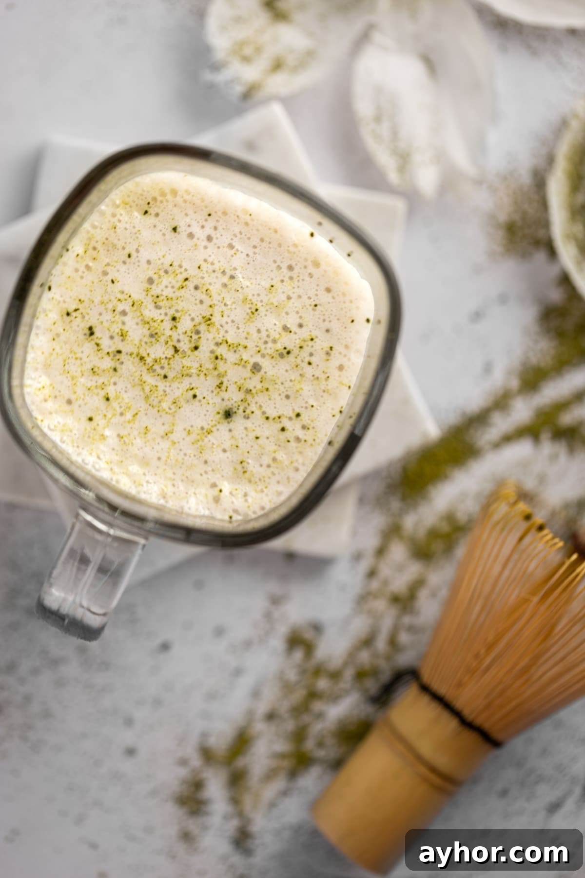 Overhead view of an almond milk matcha latte with frothed almond milk on top with a sprinkle of matcha powder.