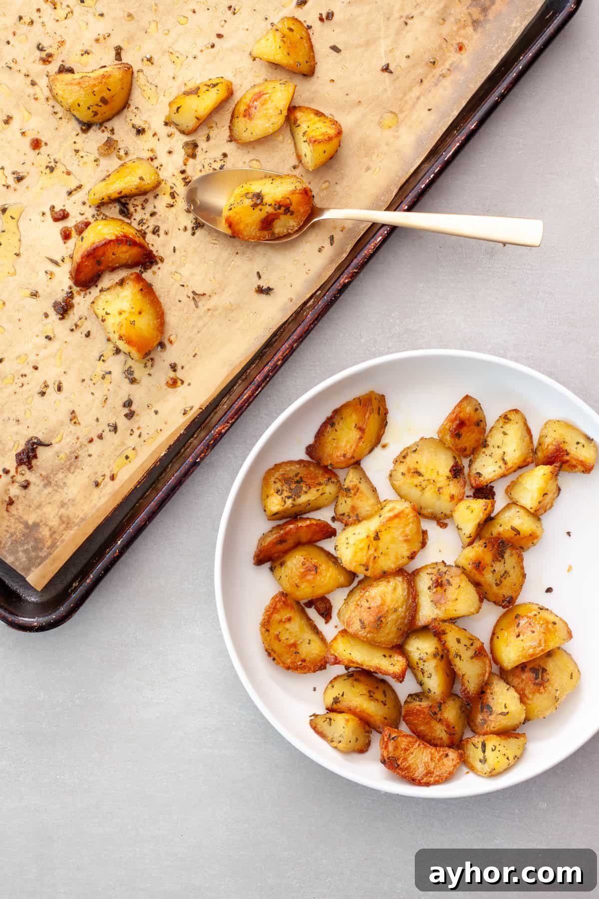 Crispy herb roasted potatoes getting transferred to a serving bowl.