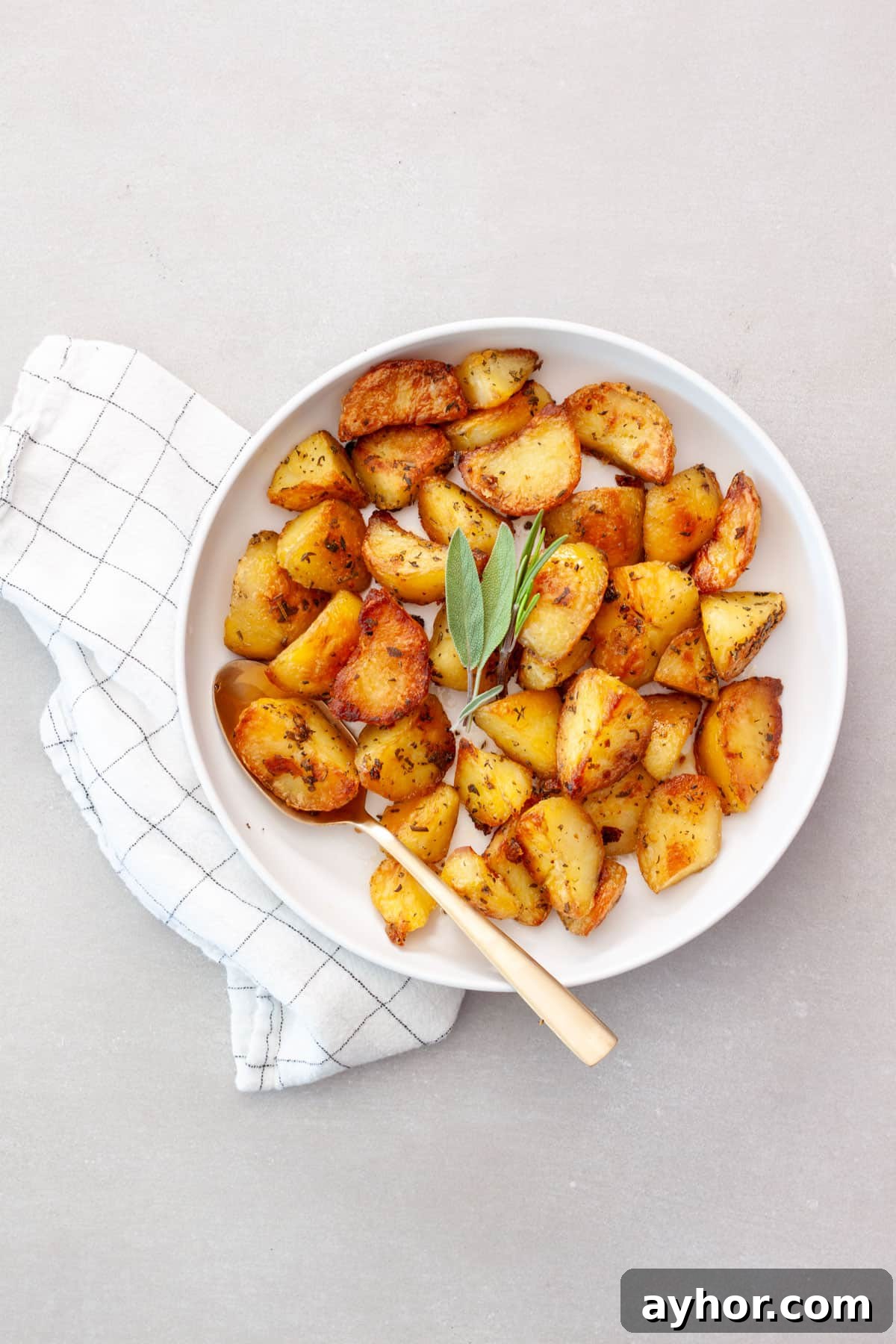 Crispy herb roasted potatoes in a serving bowl topped with fresh herbs.