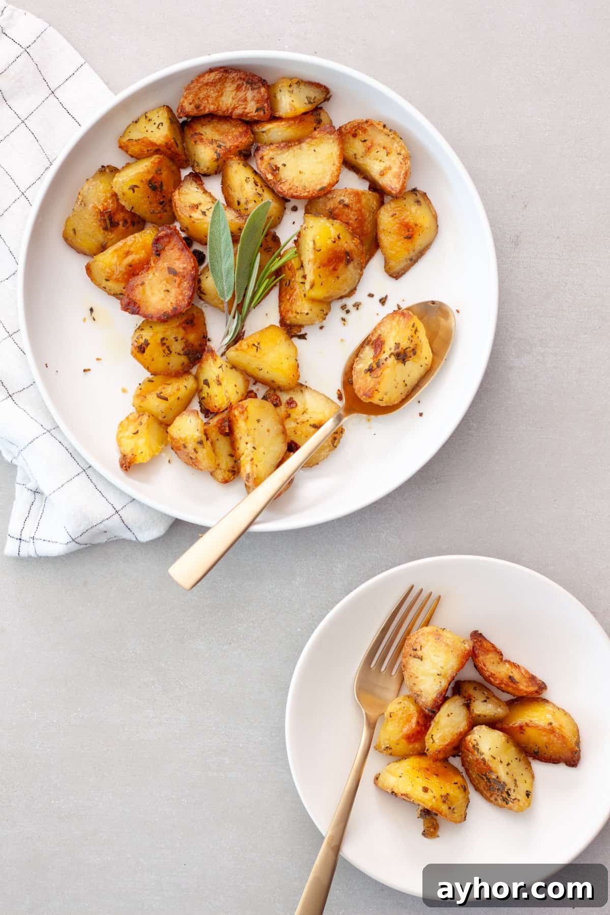 Crispy herb roasted potatoes in a large bowl getting serving to a small plate.