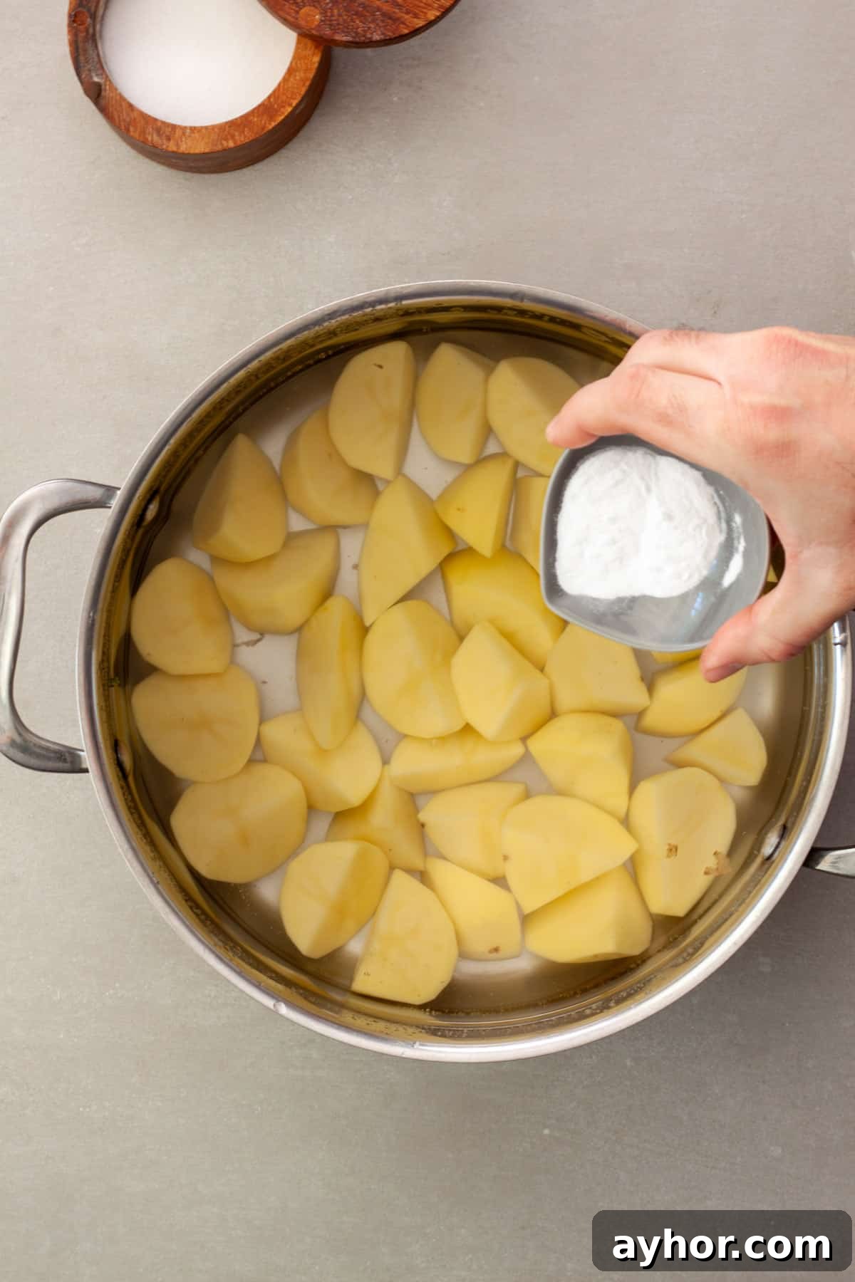 Chopped yukon gold potatoes in a pot of water with baking soda getting poured in.